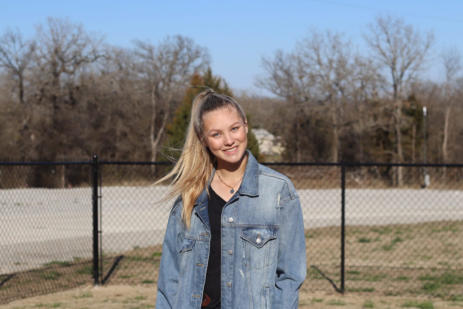 A woman standing in front of a fence. A woman standing in front of a fence.