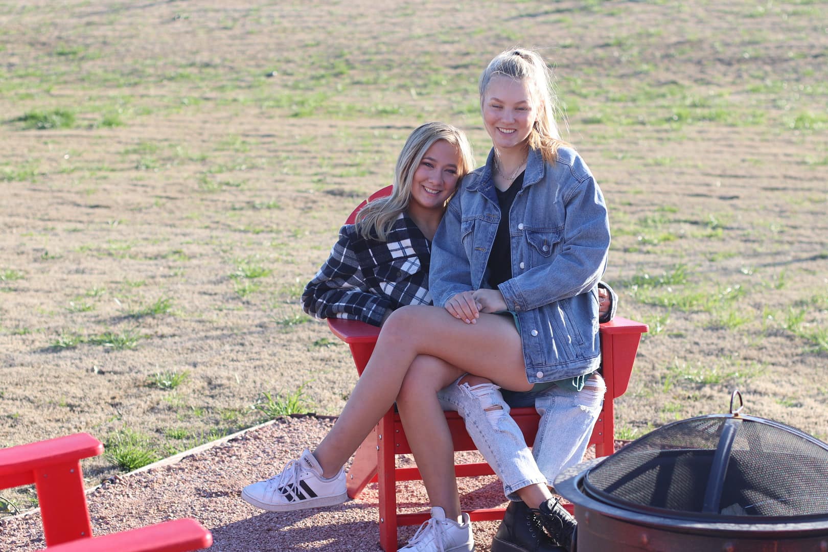 Two girls sitting on a red bench in the sun. Two girls sitting on a red bench in the sun.