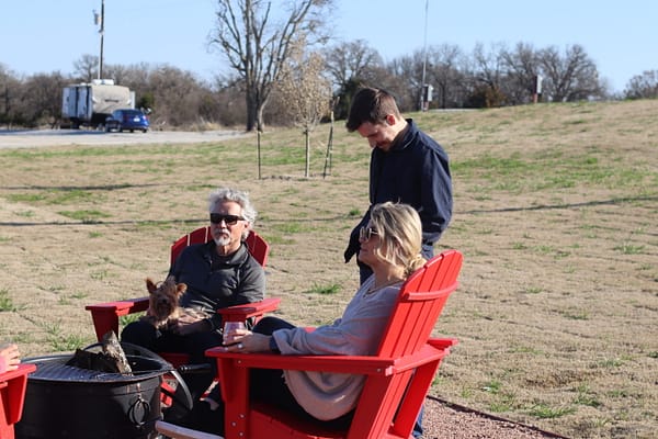 A group of people sitting around a fire pit.