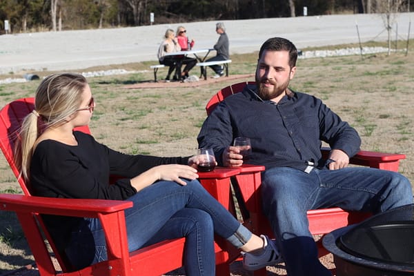 Two people sitting on red chairs talking to each other.