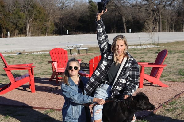 A woman and man holding up a black dog.